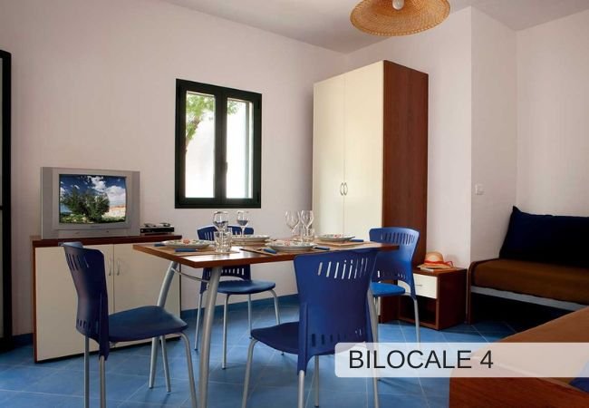 Soggiorno con tavolo da pranzo, sedie blu e televisore. Arredamento moderno.
