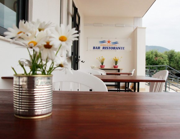 Tavolo esterno di un bar ristorante con fiori in vaso.