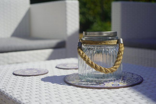 Vaso di vetro con manico in corda su tavolo in vimini.
