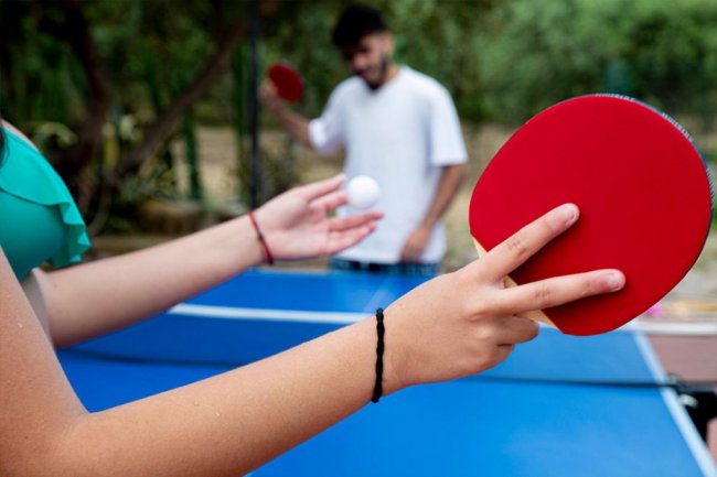Due persone giocano a ping pong all'aperto.