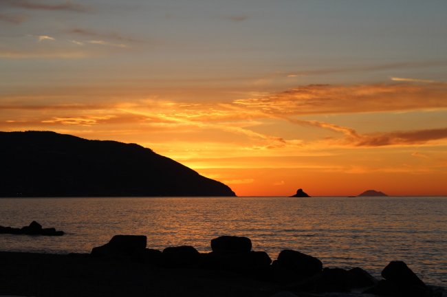 Tramonto sul mare con isole all'orizzonte.