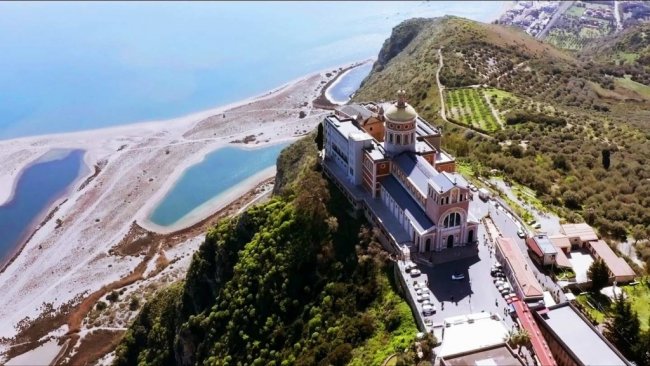 Grande edificio su una collina vicino a una spiaggia e al mare.