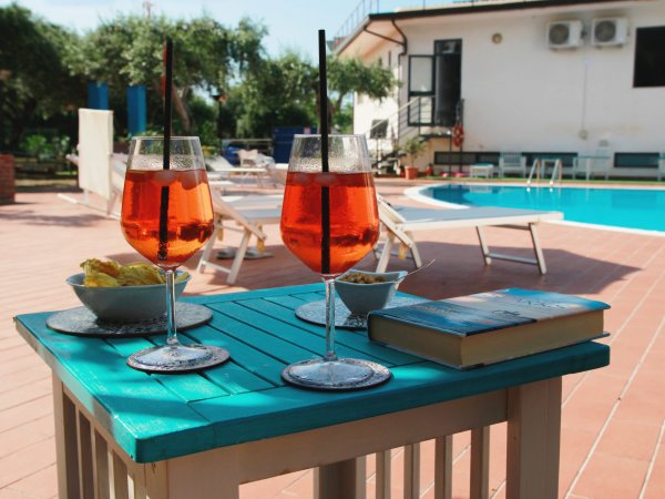 Due bicchieri di cocktail accanto a una piscina con lettini.