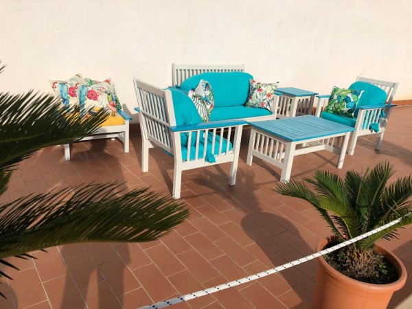 Set da giardino con divani e tavolo azzurri su terrazza.
