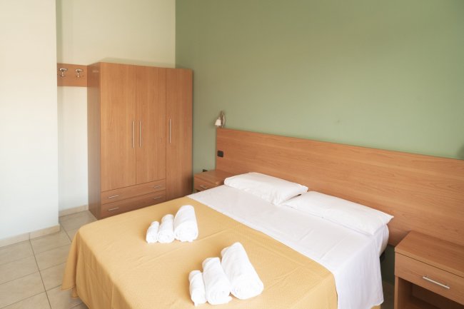 Camera da letto con letto matrimoniale e armadio beige.