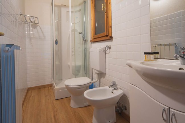Bagno con doccia, lavabo, wc e bidet. Pavimento in legno e pareti piastrellate.