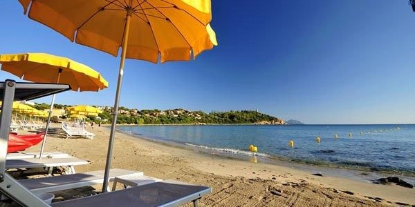 Spiaggia sabbiosa con ombrelloni gialli e mare calmo.