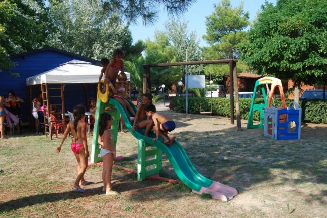 Bambini che giocano su uno scivolo verde in un parco giochi all'aperto.