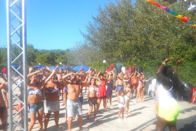 Un gruppo di persone fa esercizi all’aperto sotto un cielo azzurro.