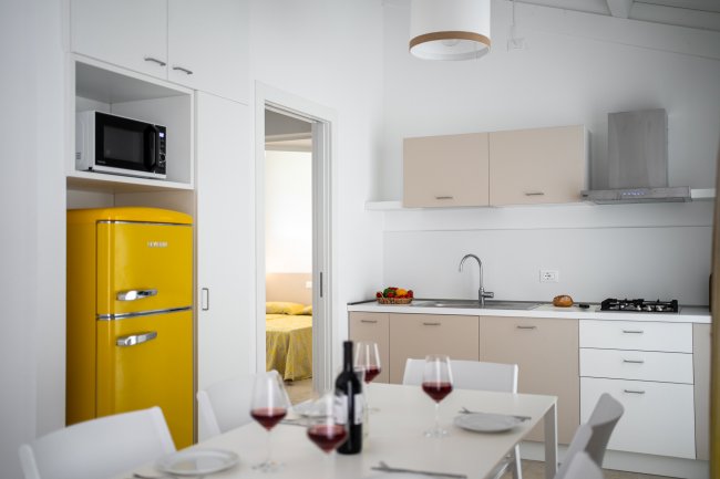 Cucina moderna con frigorifero giallo e tavolo da pranzo apparecchiato.