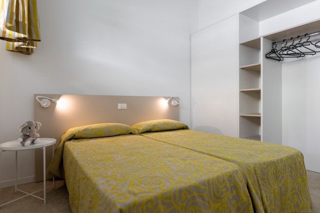 Camera da letto con letti singoli uniti e decorazioni gialle.